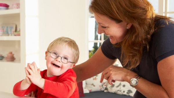 young happy child with developmental disability with caregiver