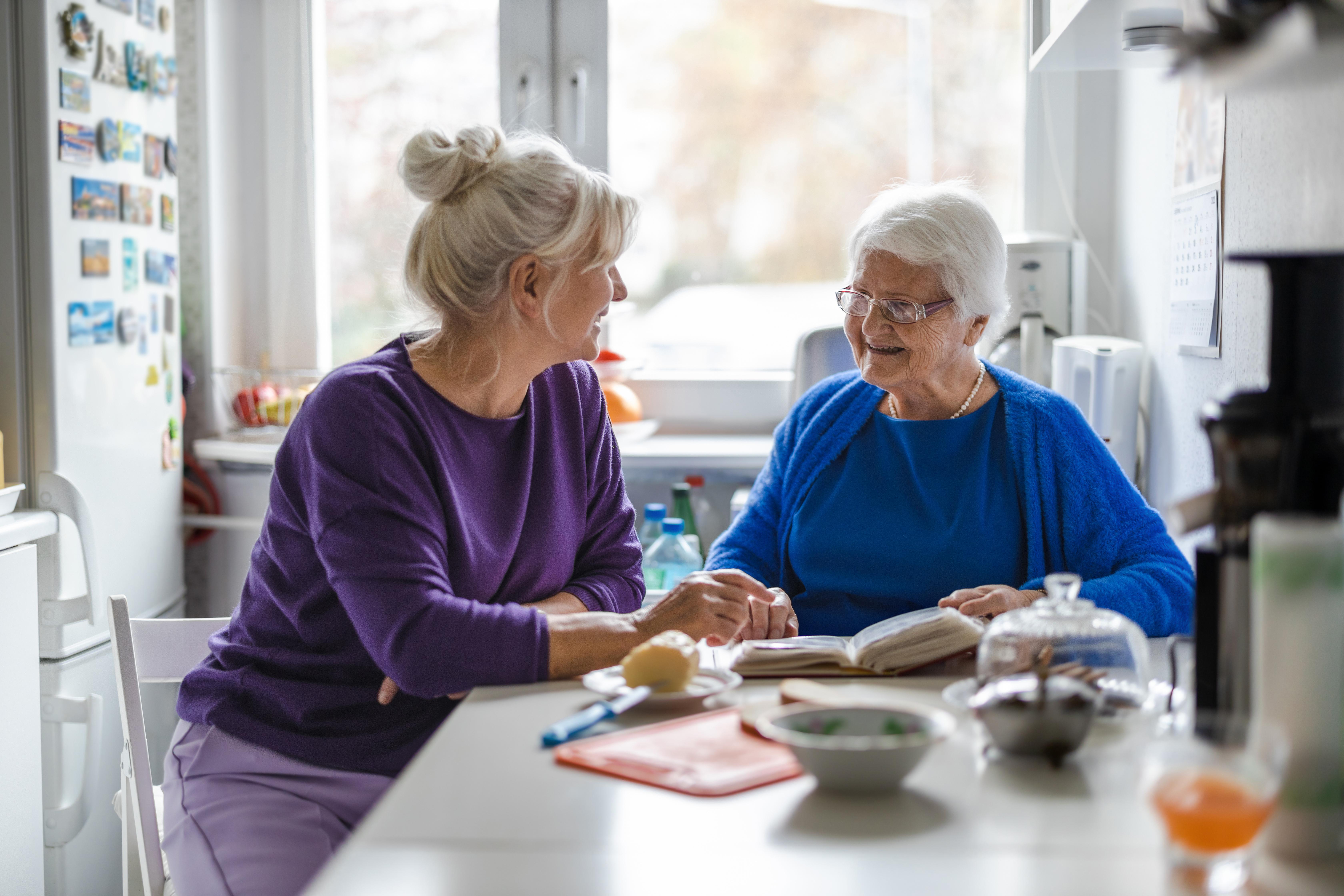 Elder woman and female companion at kitchen table